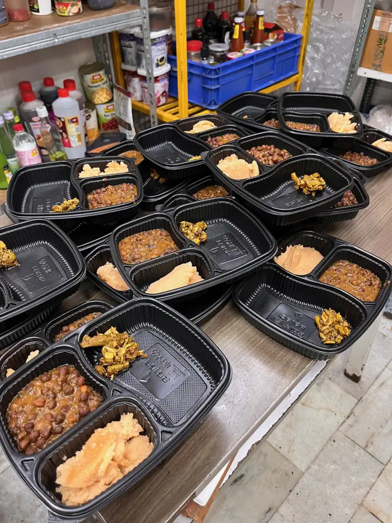 Sealed meal trays of chhole, rice and achaar stacked and ready for langar distribution